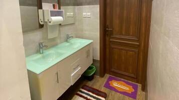 Un baño con lavabo, espejo y puerta de madera.