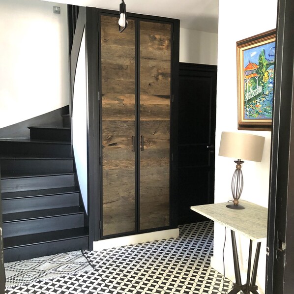 A staircase with a black railing leading to a room with a wooden door and a patterned floor. - 6-bedroom Villa with pool, 2 min from the sea. Perfect for families (Sainte Marie de Ré)