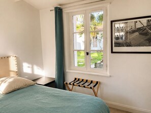 A bedroom with a bed, a window with curtains, a small bench, and a framed picture on the wall. - 6-bedroom Villa with pool, 2 min from the sea. Perfect for families (Sainte Marie de Ré)
