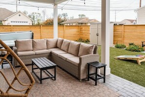 An outdoor patio with a sectional sofa, two tables, and a wicker chair. - The Jolly Rancher (Hummelstown)