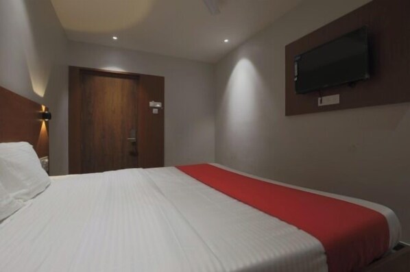 A hotel room with a bed, a television mounted on the wall, and a door. - Hotel Hi city Inn Near ISBT (Guwahati)