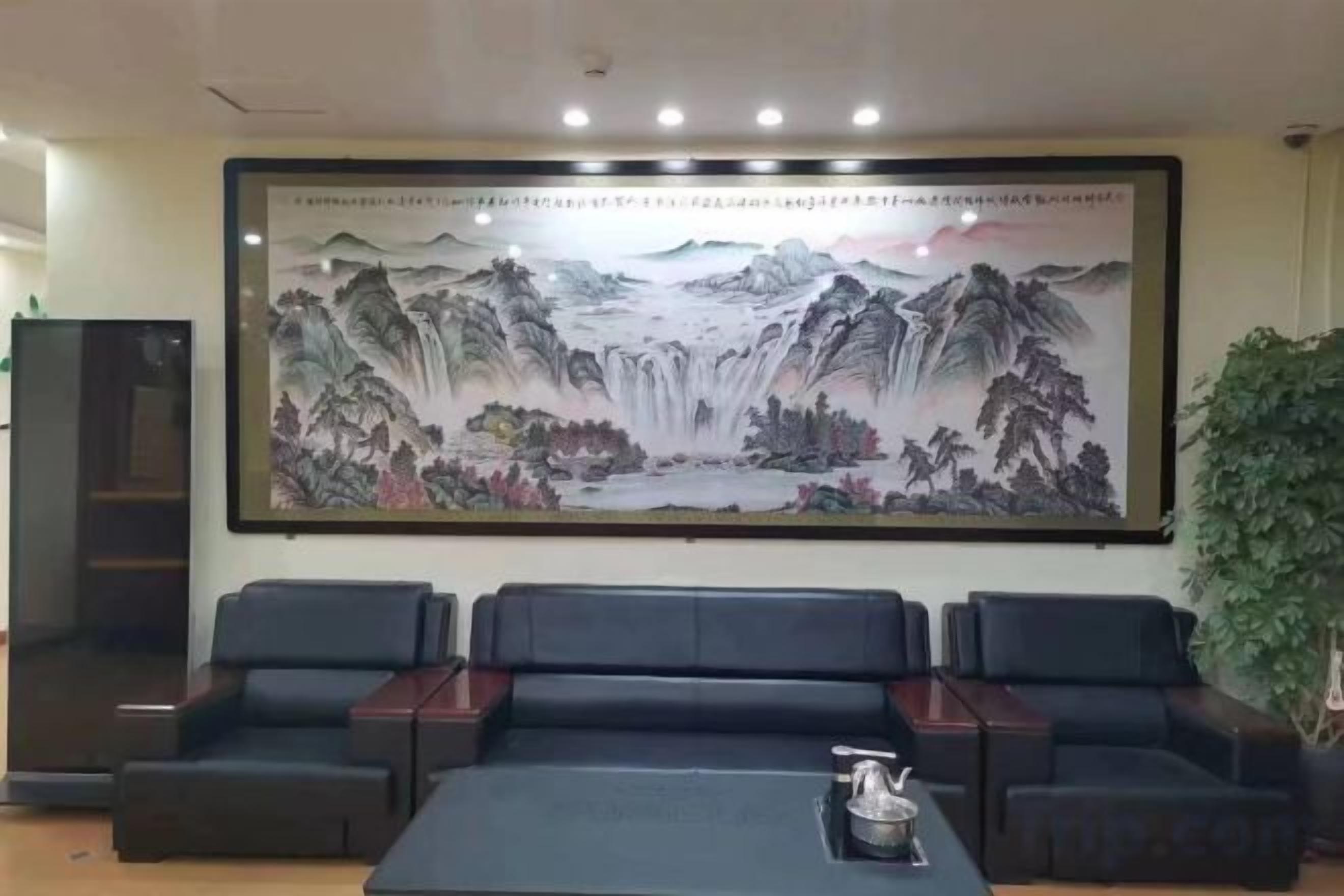 A room with a large traditional painting on the wall, a sofa, and a table with a teapot.