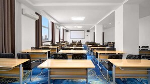 A conference room with rows of desks and chairs, a projector screen, and a large window with curtains. - Harbin Dashu Hotel (Harbin)