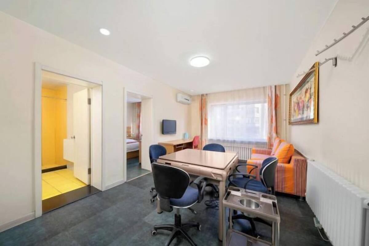 A hotel room with a bed, a desk, a chair, a table, and a window with curtains.