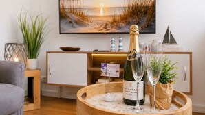 Una habitación con un armario de madera, una botella de champán y una copa sobre una mesa redonda de madera.