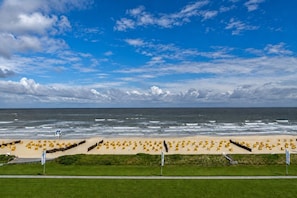 A beach with yellow chairs arranged in rows, a lifeguard tower, and a clear view of the ocean. - Luxurious penthouse Duhner Strand with sea view | Haus Hanseatic (Cuxhaven)