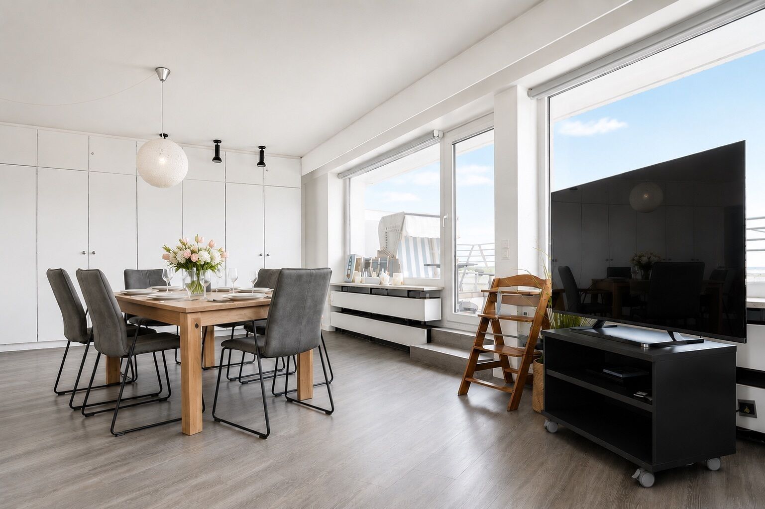 Een moderne keuken met een eethoek, grote ramen en een televisie.