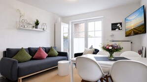 En moderne stue med sofa, stole, spisebord og et stort vindue.