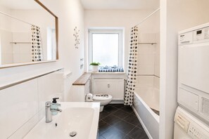 Een badkamer met een bad, toilet, wastafel en een raam met uitzicht.
