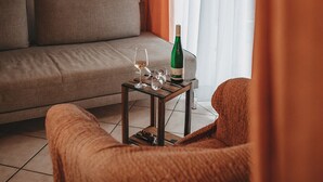 A living room with a sofa, a small table with a bottle and glasses, and a chair. - KultUrlaub Mosel GbR (Kröv)