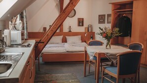 A cozy bedroom with a bed, wooden furniture, a small kitchenette, and a dining area. - KultUrlaub Mosel GbR (Kröv)