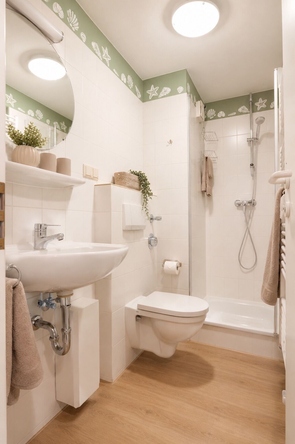 A bathroom with a sink, toilet, shower, and a mirror.