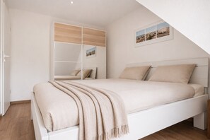 A bedroom with a bed, a mirror, and a picture on the wall.
