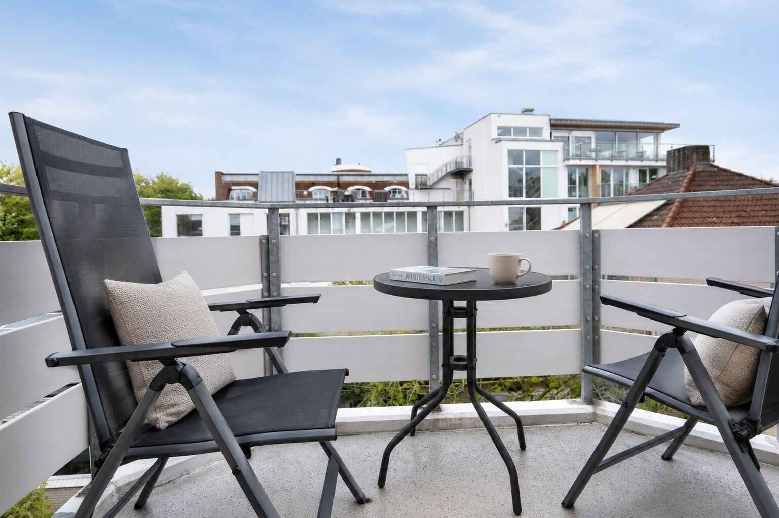 Een balkon met twee stoelen, een tafeltje en een boek.