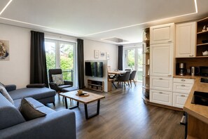 Uma sala de estar moderna com sofá, mesa de centro, televisão e área de jantar.
