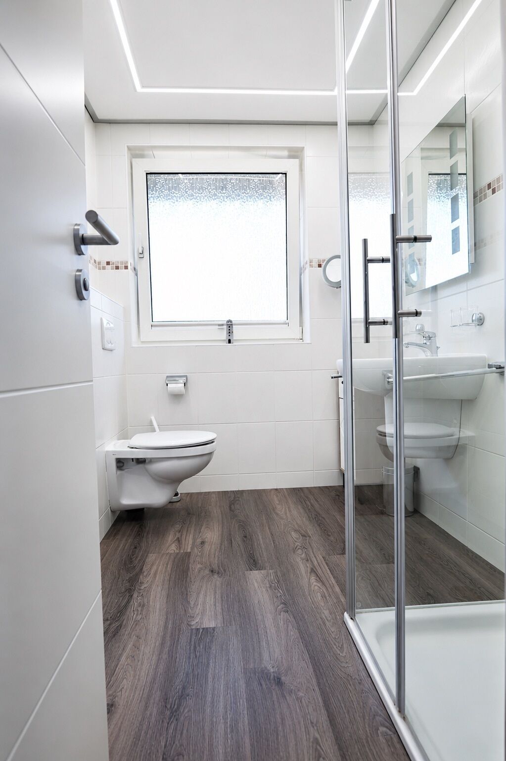 Une salle de bain moderne équipée de toilettes, d’un lavabo et d’un espace douche.