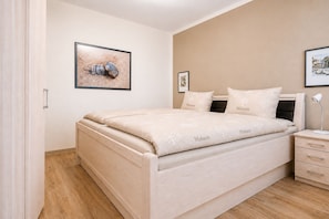 Une chambre à coucher avec un lit, des tables de chevet, une commode et deux tableaux encadrés accrochés au mur.