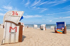 Una playa con sillas y sombrillas, algunas con números y letras.