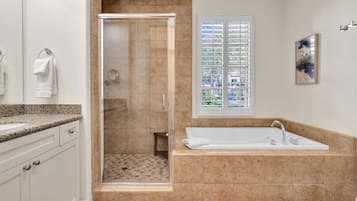 A bathroom with a walk-in shower, a bathtub, and a window with a view of buildings.