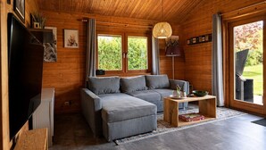 Ein modernes Blockhaus-Interieur mit grauem Sofa, Holztisch und Fernseher.