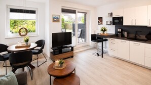 A modern kitchen with white cabinets, a black countertop, and a built-in oven. - Vacation apartment Cuxhaven-Döse-Duhnen near the beach with sauna, south-facing terrace & beach chair (Cuxhaven)