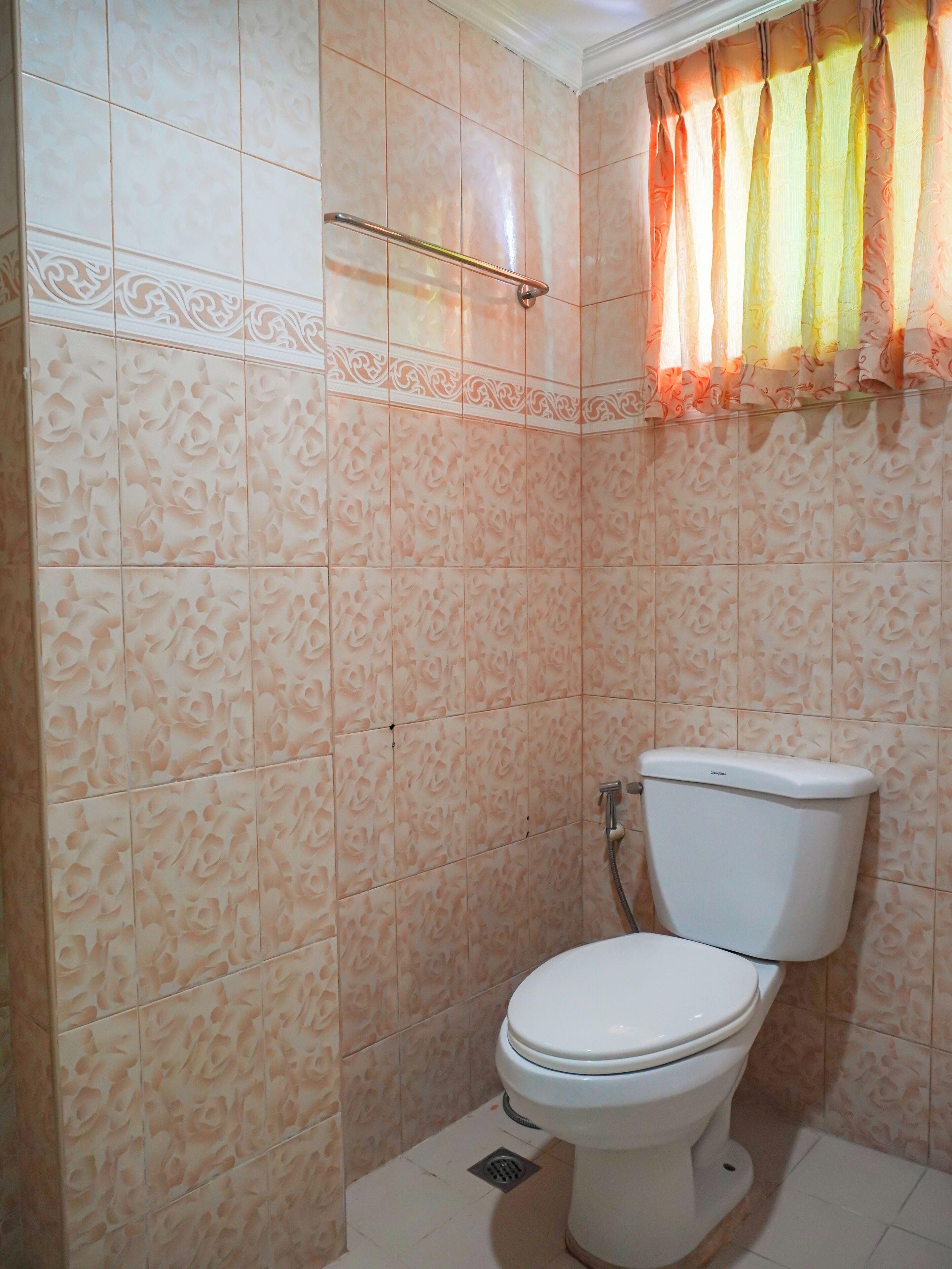 A bathroom with a toilet, a shower curtain, and patterned tiles.
