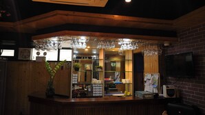 A reception area with a wooden counter, glass display cases, and hanging glassware. - Boracay Paradise Hotel (Boracay Island)