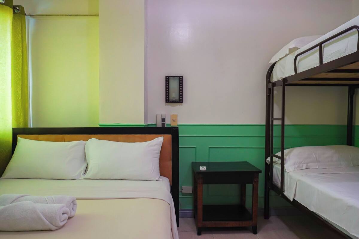 Ein Hotelzimmer mit einem Einzelbett, einem Etagenbett und einem kleinen Tisch.