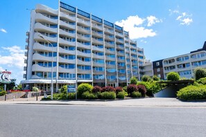 Een meerhoog hotel met balkons, een zichtbaar restaurantbord en een parkeerplaats.
