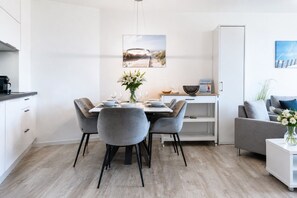 Een moderne keuken met een eethoek, witte kastjes en uitzicht op de omgeving.