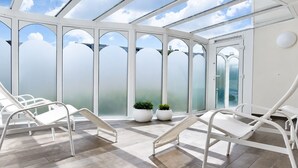 A conservatory with white metal chairs, a tiled floor, and potted plants. - Vacation apartment Cuxhaven Döse on the beach | Lord Nelson No. 310 (Cuxhaven)