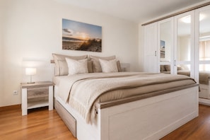 A bedroom with a bed, nightstands, a wardrobe, and a painting on the wall.