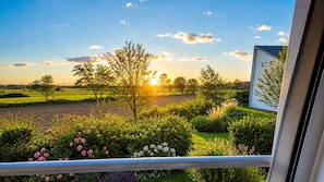 A balcony with a view of a garden and fields during sunset. - Duhner Horizonte vacation apartment in Duhnen on the North Sea with loggia (Cuxhaven)