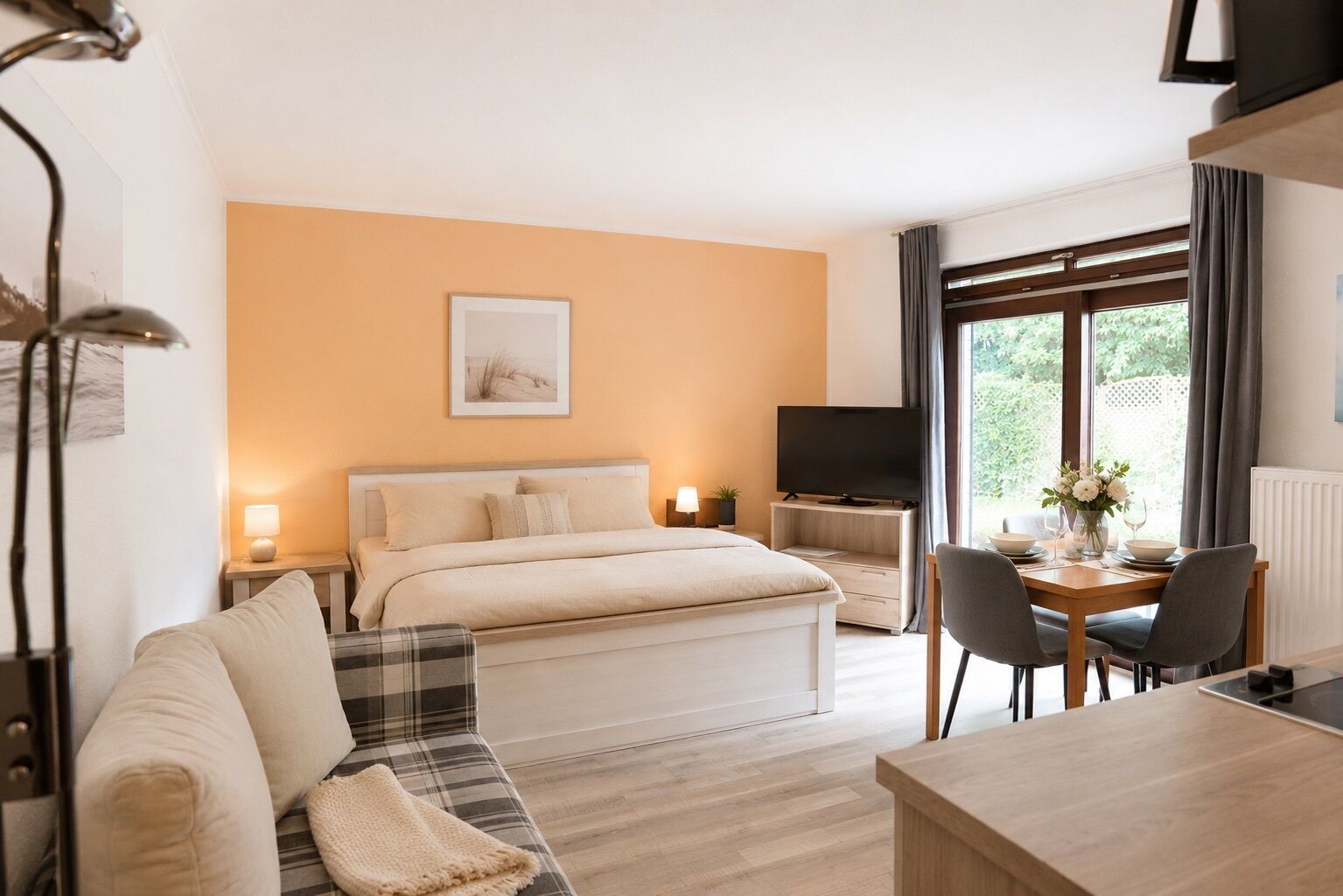 A hotel room with a bed, a sofa, a dining table with chairs, a TV, and a window with curtains.