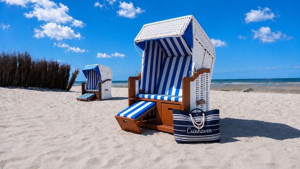 Beach chairs with striped cushions and a beach bag labeled 'Cuxhaven' on a sandy beach.