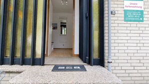 A hotel entrance with a signboard, a door with curtains, and a brick wall.