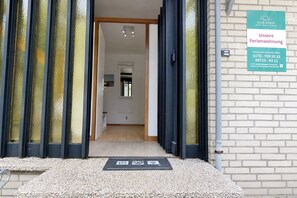 A hotel entrance with a signboard, a door with curtains, and a brick wall.