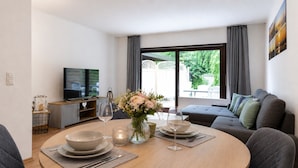 A dining area with a round table, chairs, a TV, and a sofa.