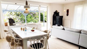 A dining area with a white table, six chairs, and a hanging light fixture.