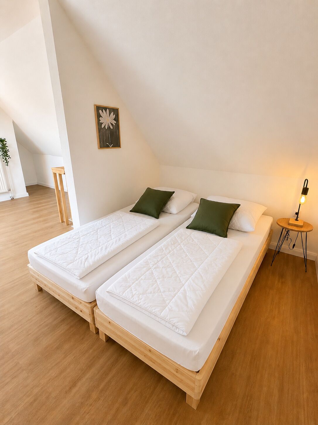 Une chambre double avec deux lits, une petite table et un tableau accroché au mur.