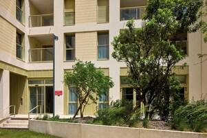 Un immeuble à plusieurs étages doté de balcons, d’un escalier et d’un jardin bien entretenu.