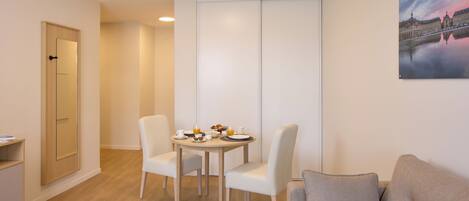 A modern room with a dining table, two chairs, a sofa, and a cabinet.
