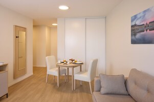 Une pièce moderne comprenant une table à manger, deux chaises, un canapé et un meuble.