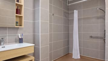 A modern bathroom with a shower, a sink, and a shelf with toiletries.
