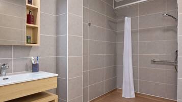 A modern bathroom with a shower, a sink, and a shelf with toiletries.