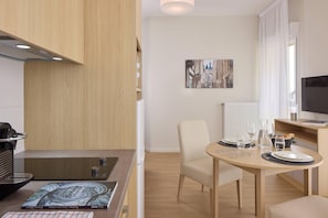 Una cocina moderna con estufa integrada, un comedor con una mesa para dos personas y un cuadro en la pared.