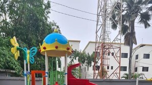 A playground with colorful equipment, including slides and climbing structures, surrounded by greenery and a building in the background. - Aquaview Apartments (Serrekunda)