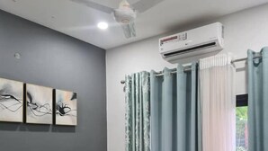 A bedroom with a bed, a ceiling fan, an air conditioner, and curtains. - Aquaview Apartments (Serrekunda)