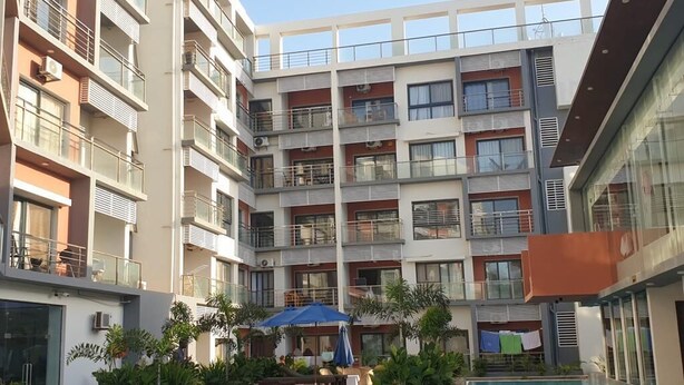 A multi-story residential building with balconies, a swimming pool, and outdoor seating areas. - Aquaview Apartments (Serrekunda)