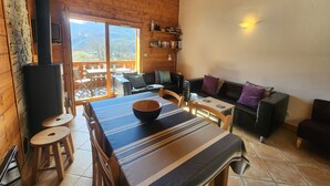 A cozy wooden cabin with a dining area, a sofa, and a fireplace. - 4-room apartment with Wifi and parking in Samoëns (Samoëns)